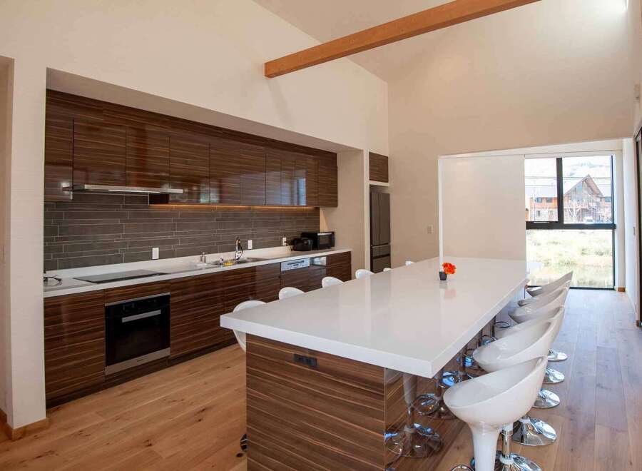 This modern kitchen boasts sleek, dark wood cabinetry and a spacious island with seating, perfect for entertaining.