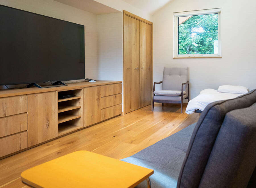 This modern living space features a large flat-screen TV mounted on a custom wooden entertainment unit, perfect for movie nights.