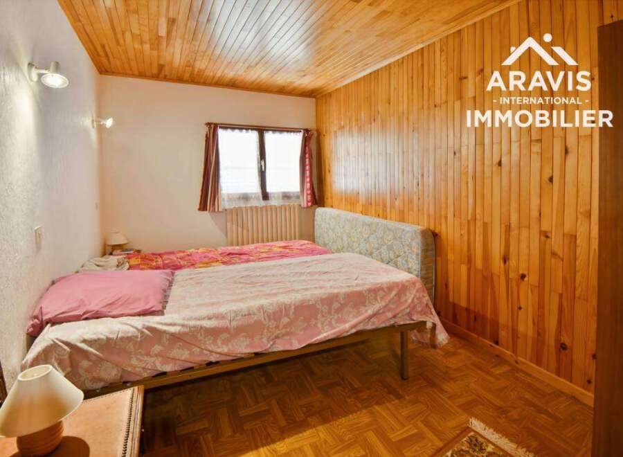 Discover this charming bedroom featuring a cozy wooden ceiling and walls, creating a warm and inviting atmosphere.