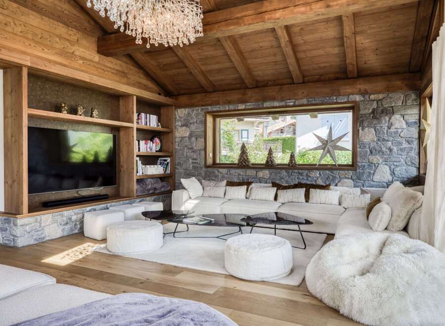 Experience luxury living in this stunning property, featuring a cozy living room with a stone fireplace and wooden ceiling.
