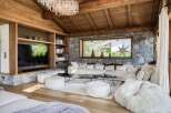 Experience luxury living in this stunning property, featuring a cozy living room with a stone fireplace and wooden ceiling.