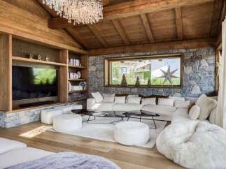 Experience luxury living in this stunning property, featuring a cozy living room with a stone fireplace and wooden ceiling.