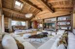 Experience luxury living in this stunning chalet, featuring a warm and inviting interior with exposed wooden beams and a cozy fireplace.