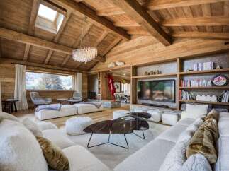Experience luxury living in this stunning chalet, featuring a warm and inviting interior with exposed wooden beams and a cozy fireplace.