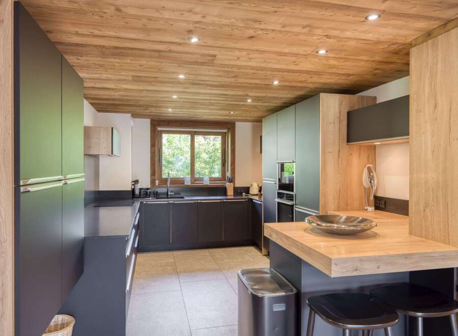 This modern kitchen features a stunning wooden ceiling and sleek, dark cabinetry, creating a warm and inviting atmosphere.