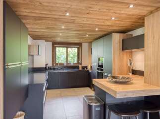 This modern kitchen features a stunning wooden ceiling and sleek, dark cabinetry, creating a warm and inviting atmosphere.