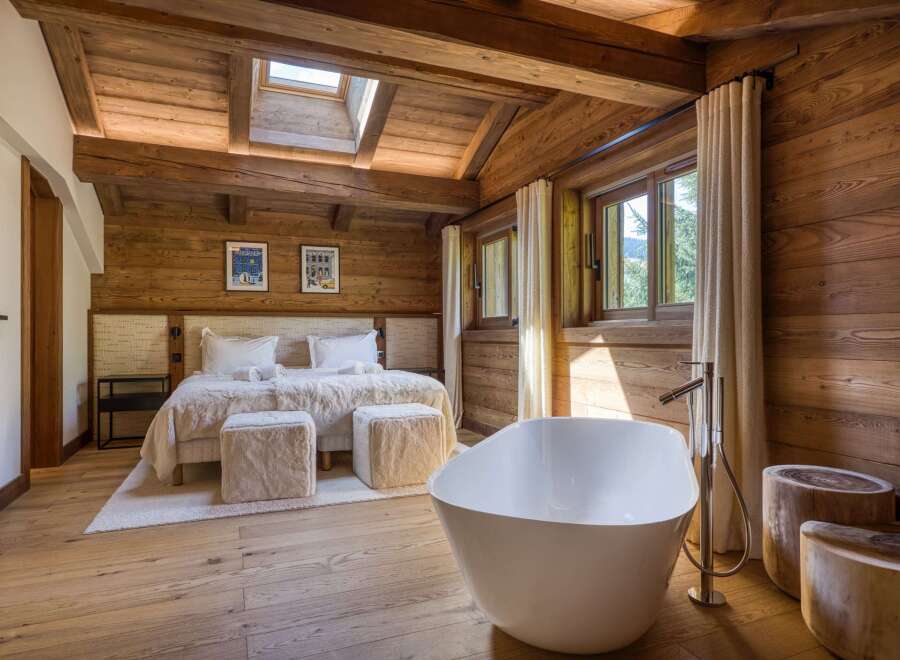 Experience luxury in this stunning bedroom featuring a freestanding bathtub and a cozy bed.