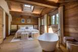 Experience luxury in this stunning bedroom featuring a freestanding bathtub and a cozy bed.