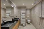 This modern bathroom boasts a sleek design with its dark sinks and neutral-toned tiles.