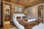 This cozy bedroom features a beautiful wooden ceiling and walls, creating a warm and inviting atmosphere.