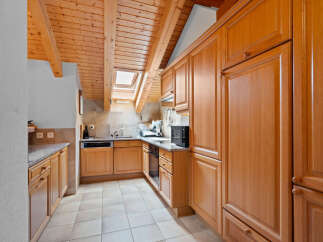 This charming kitchen boasts a warm and inviting atmosphere with its wooden ceiling and cabinetry.
