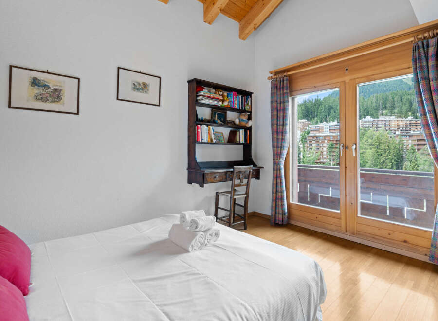 This charming bedroom features a cozy desk area and a stunning view.