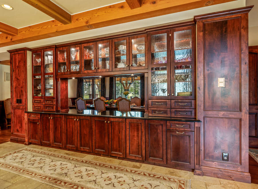 This stunning property boasts a custom-built kitchen with rich, dark wood cabinetry and glass-fronted display cabinets, perfect for showcasing your finest china and glassware.