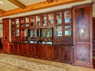 This stunning property boasts a custom-built kitchen with rich, dark wood cabinetry and glass-fronted display cabinets, perfect for showcasing your finest china and glassware.