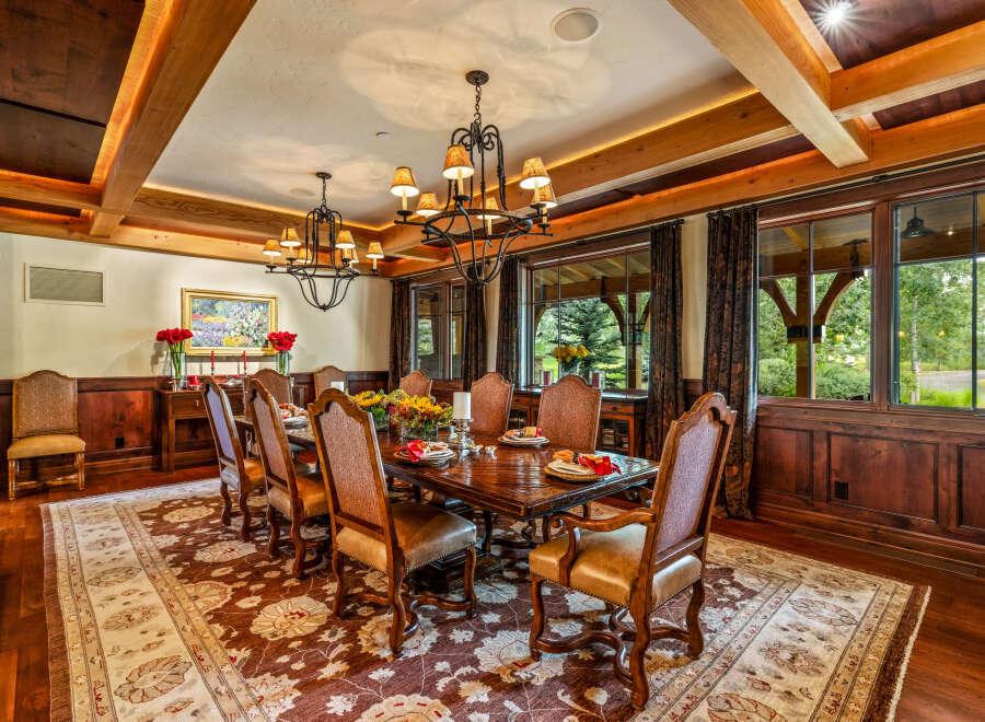 Step into luxury with this exquisite dining room, featuring a stunning chandelier and elegant wooden accents.