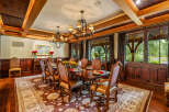 Step into luxury with this exquisite dining room, featuring a stunning chandelier and elegant wooden accents.