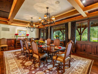 Step into luxury with this exquisite dining room, featuring a stunning chandelier and elegant wooden accents.