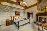 Experience luxury in this stunning bedroom featuring a stone accent wall and a cozy fireplace.