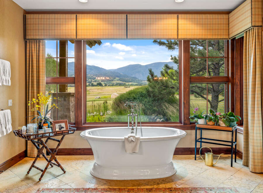 Indulge in luxury with this stunning bathroom featuring a freestanding tub and breathtaking mountain views.