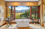 Indulge in luxury with this stunning bathroom featuring a freestanding tub and breathtaking mountain views.