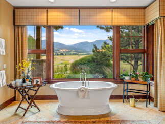 Indulge in luxury with this stunning bathroom featuring a freestanding tub and breathtaking mountain views.