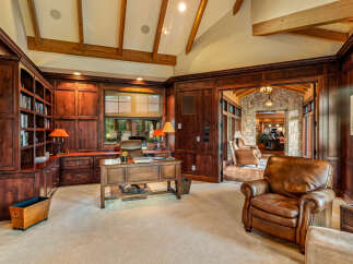 This luxurious home office exudes sophistication with its rich wood paneling and built-in bookshelves.