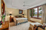 Experience luxury in this stunning bedroom featuring a wrought iron bed, elegant lamps, and a serene view.