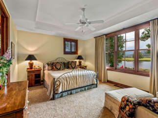 Experience luxury in this stunning bedroom featuring a wrought iron bed, elegant lamps, and a serene view.