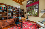 Step into luxury with this stunning home office, featuring custom built-in bookshelves, a classic desk, and a vibrant red rug.