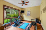 This stunning home gym offers a serene workout experience with its expansive windows overlooking lush greenery.