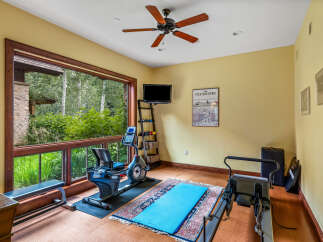 This stunning home gym offers a serene workout experience with its expansive windows overlooking lush greenery.