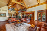 Experience luxury living in this stunning property, featuring a grand living room with soaring ceilings and exposed wooden beams.