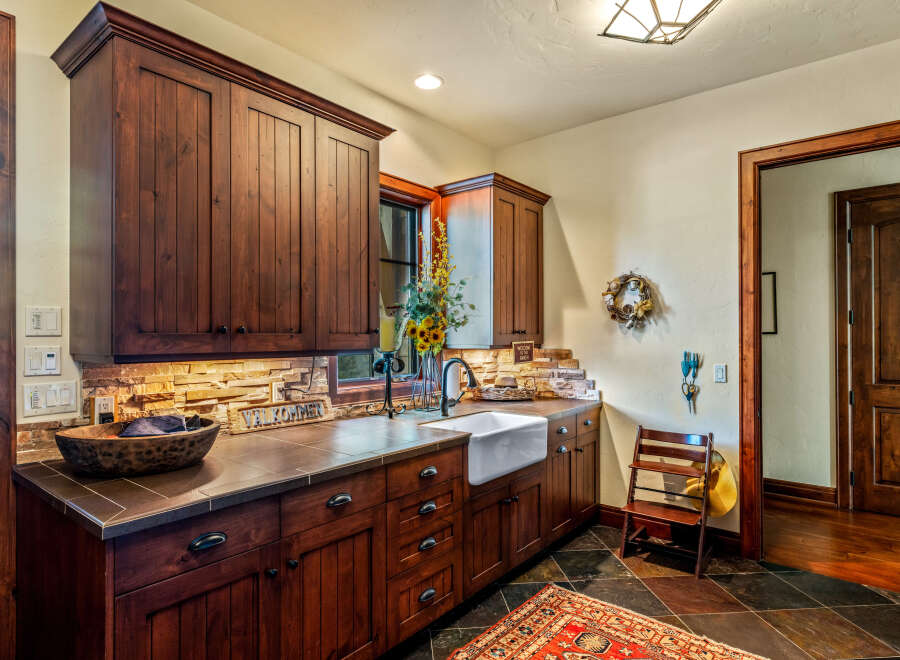 This stunning kitchen boasts custom wood cabinetry, a farmhouse sink, and a beautiful stone backsplash, creating a warm and inviting atmosphere.