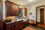 This stunning kitchen boasts custom wood cabinetry, a farmhouse sink, and a beautiful stone backsplash, creating a warm and inviting atmosphere.