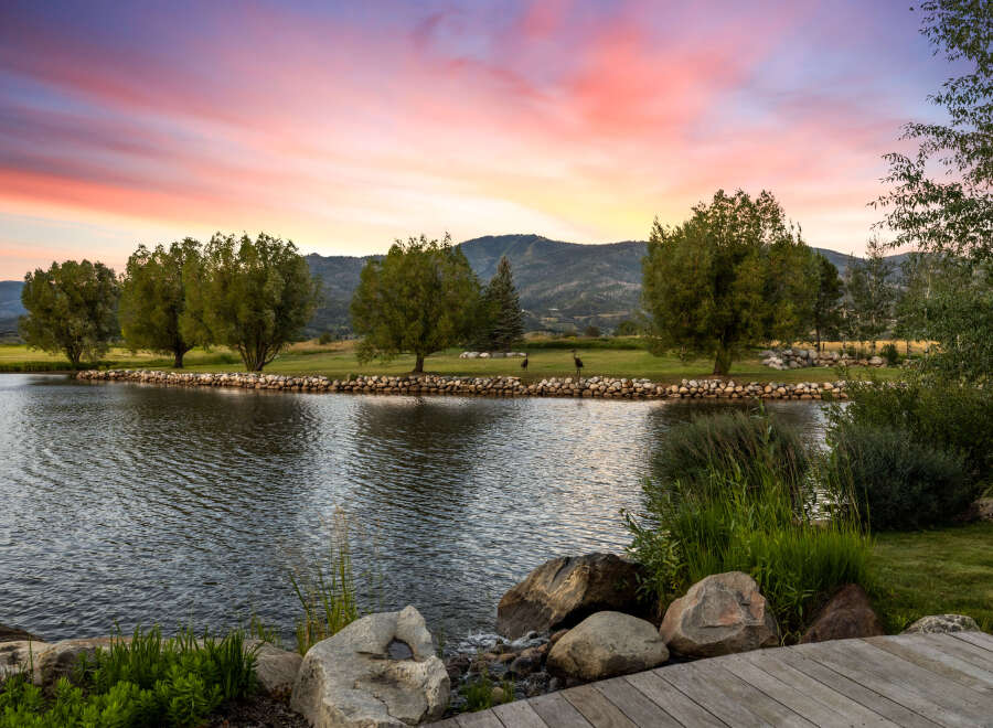 Experience tranquility at this stunning property, featuring a serene lake and lush greenery.