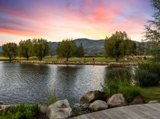 Experience tranquility at this stunning property, featuring a serene lake and lush greenery.