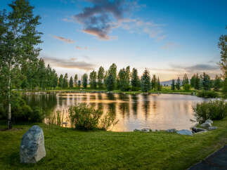 This stunning property features a serene lake surrounded by lush greenery and mature trees, creating a tranquil oasis.