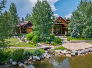 This stunning property showcases a luxurious home nestled amidst lush landscaping and a serene pond.