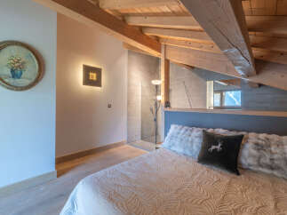 This cozy bedroom boasts a unique design with exposed wooden beams and a stylish accent wall.