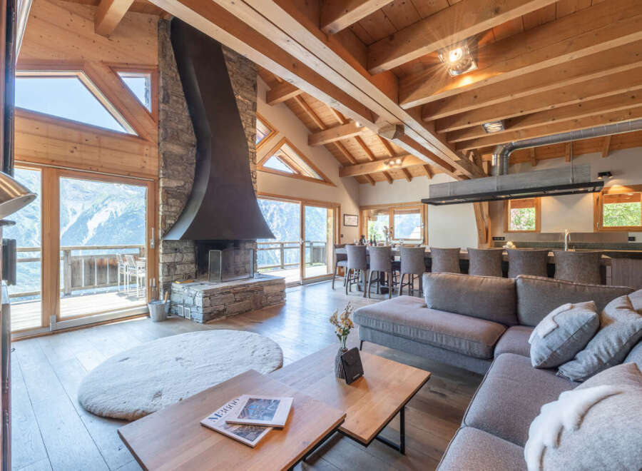 Experience luxury living in this stunning chalet, featuring a grand stone fireplace and expansive windows that frame breathtaking mountain views.