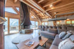 Experience luxury living in this stunning chalet, featuring a grand stone fireplace and expansive windows that frame breathtaking mountain views.