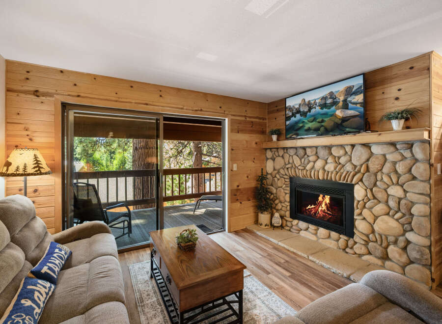 Cozy up in this charming living room featuring a stunning stone fireplace and a large flat-screen TV.