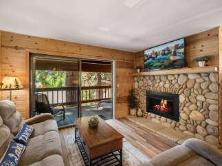 Cozy up in this charming living room featuring a stunning stone fireplace and a large flat-screen TV.