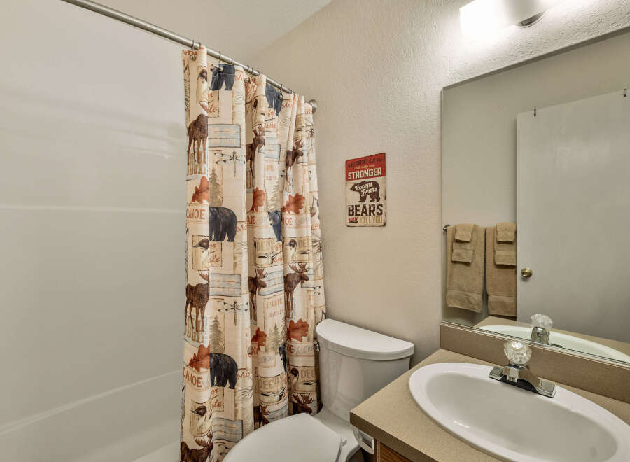 This charming bathroom features a rustic shower curtain with nature-themed designs, creating a cozy and inviting atmosphere.