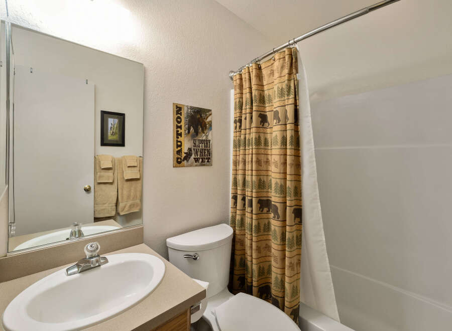 This charming bathroom features a rustic bear-themed shower curtain, adding a touch of nature-inspired design.