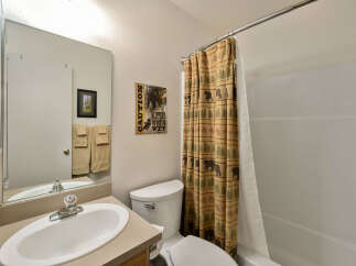 This charming bathroom features a rustic bear-themed shower curtain, adding a touch of nature-inspired design.