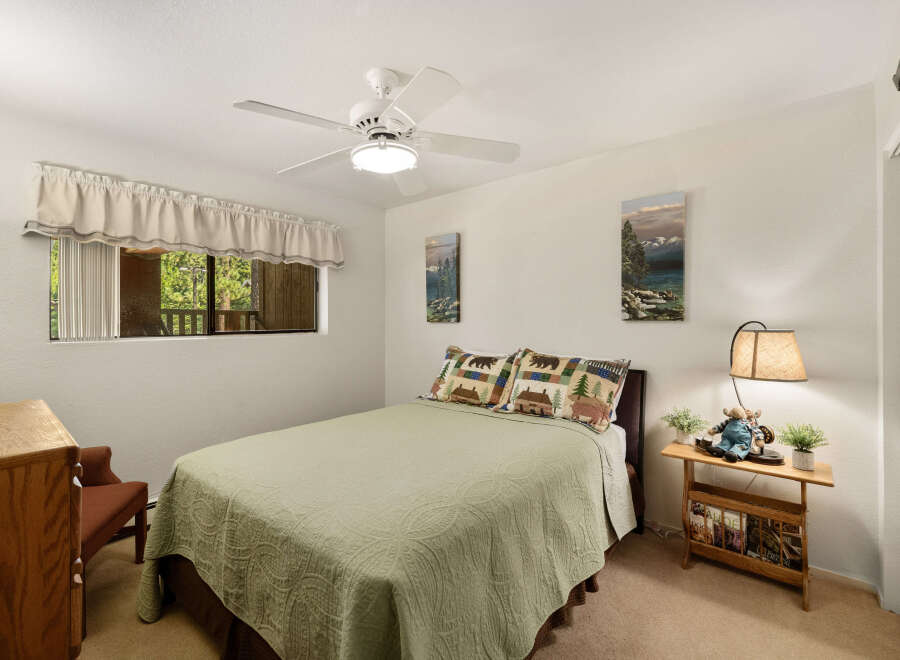 This cozy bedroom features a comfortable bed with a green quilt and decorative pillows.