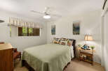 This cozy bedroom features a comfortable bed with a green quilt and decorative pillows.