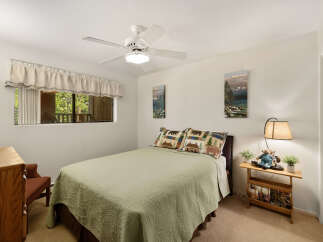 This cozy bedroom features a comfortable bed with a green quilt and decorative pillows.