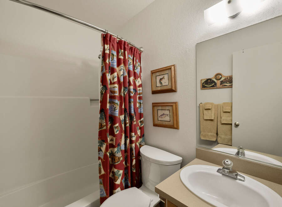 This charming bathroom features a cozy design with a red patterned shower curtain, adding a touch of personality to the space.